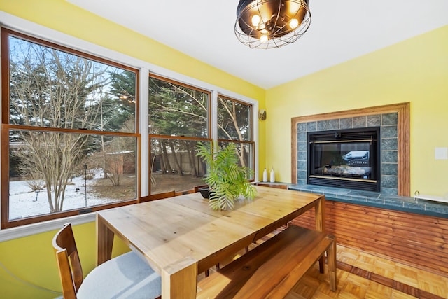 dining area with parquet flooring, plenty of natural light, a chandelier, and a fireplace