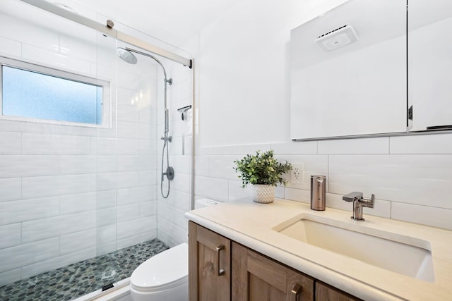 bathroom featuring tile walls, tasteful backsplash, toilet, walk in shower, and vanity