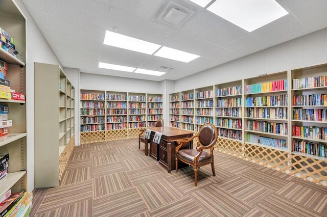 living area with carpet floors and a drop ceiling