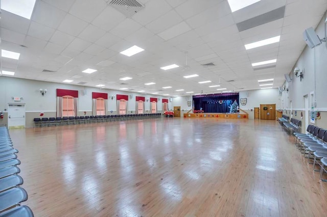 gym with a paneled ceiling and light hardwood / wood-style flooring