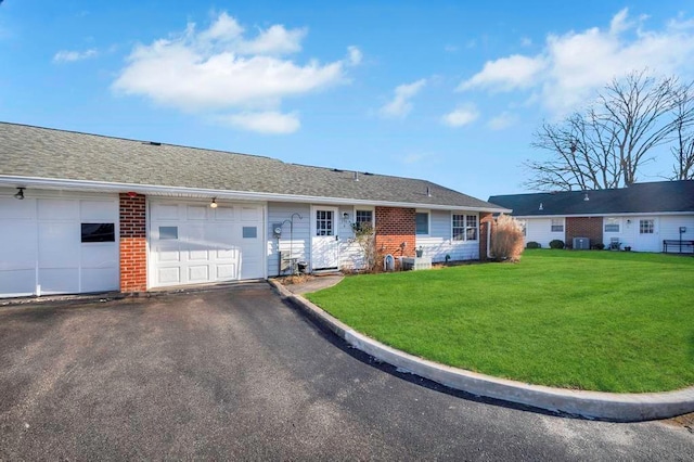 ranch-style home with cooling unit, a garage, and a front yard