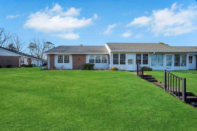 rear view of property featuring a sunroom and a yard