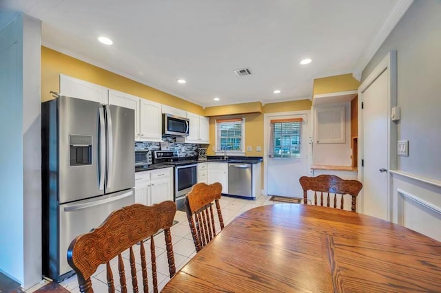 kitchen featuring sink, decorative backsplash, light tile patterned floors, appliances with stainless steel finishes, and white cabinetry