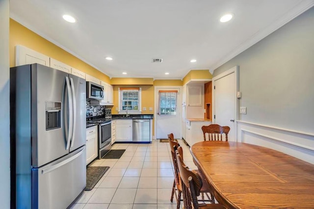 kitchen featuring stainless steel appliances, crown molding, sink, light tile patterned floors, and white cabinets