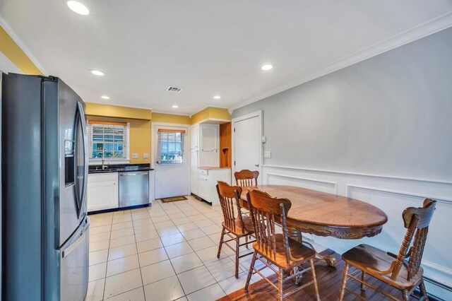 interior space featuring white cabinetry, sink, stainless steel appliances, crown molding, and light tile patterned floors