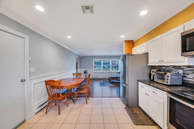 kitchen with decorative backsplash, appliances with stainless steel finishes, ornamental molding, light tile patterned floors, and white cabinetry