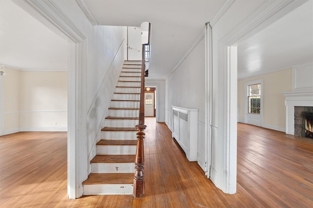 stairs with hardwood / wood-style floors and crown molding