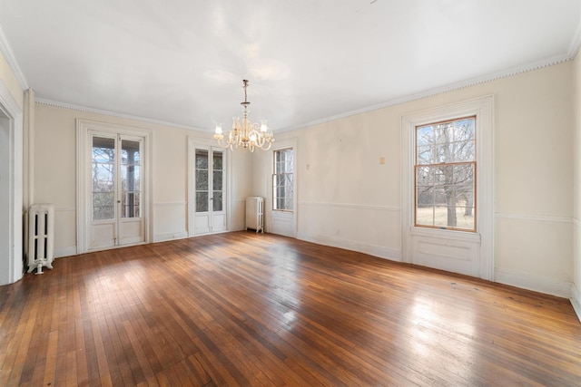 unfurnished room featuring hardwood / wood-style flooring, an inviting chandelier, and radiator heating unit