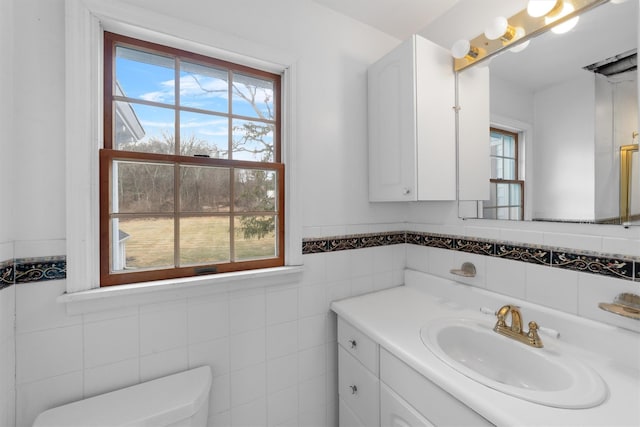 bathroom featuring tile walls, vanity, and toilet