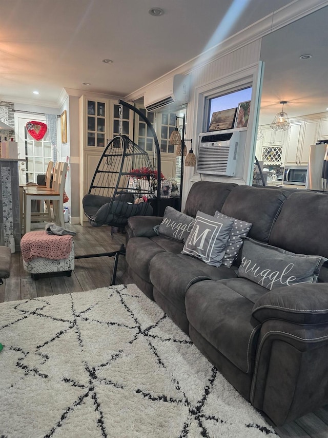 living room with cooling unit, an AC wall unit, ornamental molding, and hardwood / wood-style flooring