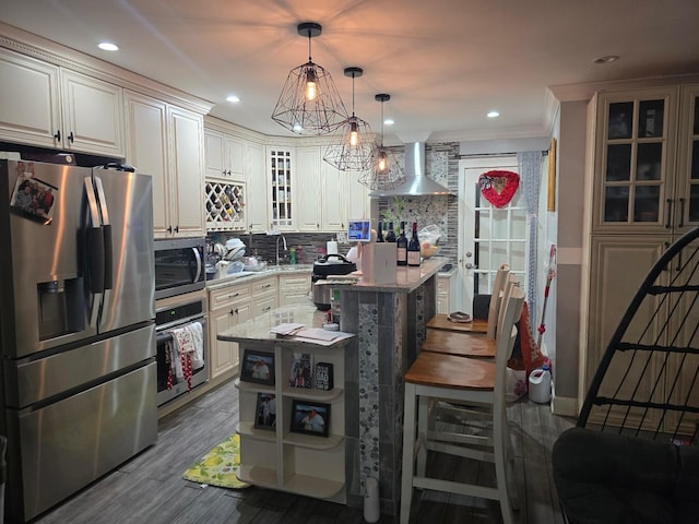 kitchen with a center island, appliances with stainless steel finishes, a breakfast bar area, wall chimney exhaust hood, and light stone counters