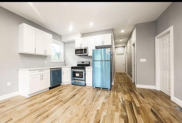 kitchen with white cabinets, stainless steel appliances, and light hardwood / wood-style flooring