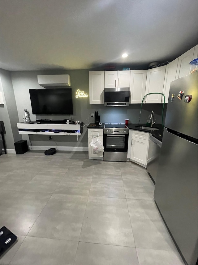 kitchen featuring an AC wall unit, white cabinetry, sink, and stainless steel appliances