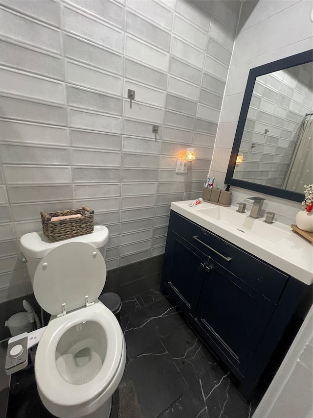 bathroom featuring vanity, toilet, and tile walls