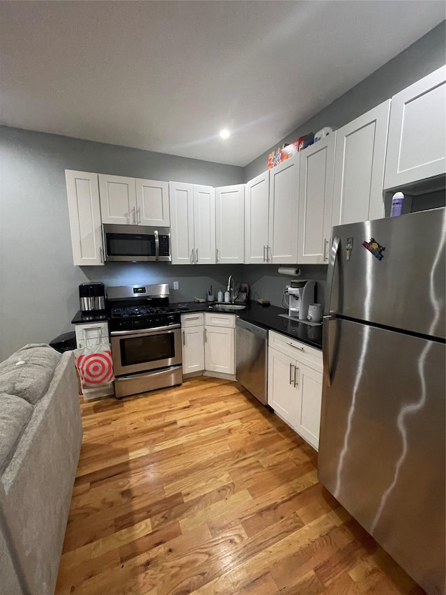 kitchen featuring white cabinets, stainless steel appliances, light hardwood / wood-style floors, and sink