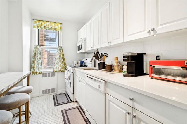 5635 Netherland Ave Unit 4E, Bronx, NY 10471 - kitchen featuring radiator, white cabinetry, and white appliances