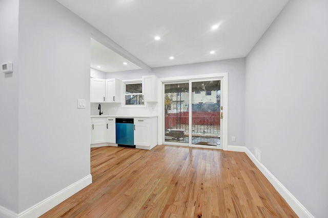 kitchen with dishwasher, light wood-type flooring, white cabinets, and sink