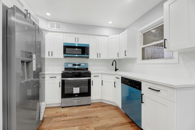 kitchen featuring appliances with stainless steel finishes, white cabinetry, light hardwood / wood-style flooring, and sink