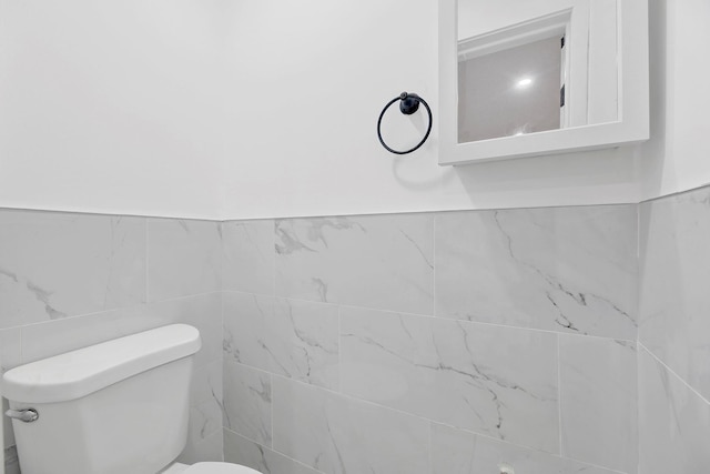 bathroom featuring toilet and tile walls