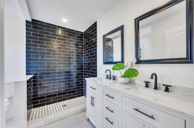 bathroom with a tile shower, vanity, and tile patterned floors