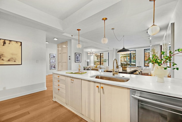 kitchen featuring sink, hanging light fixtures, stainless steel dishwasher, a notable chandelier, and light hardwood / wood-style floors