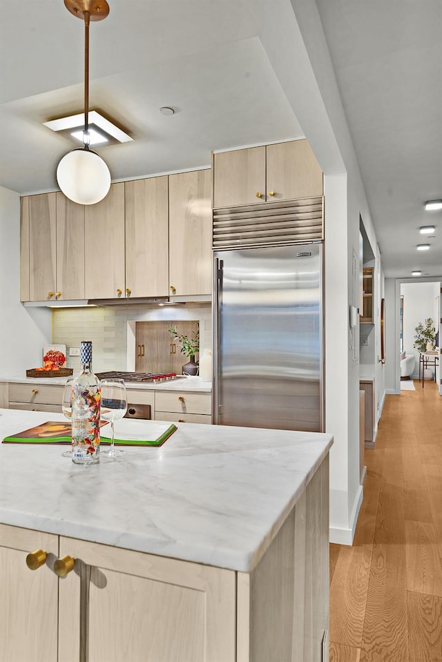 kitchen with built in fridge, light brown cabinets, and light wood-type flooring