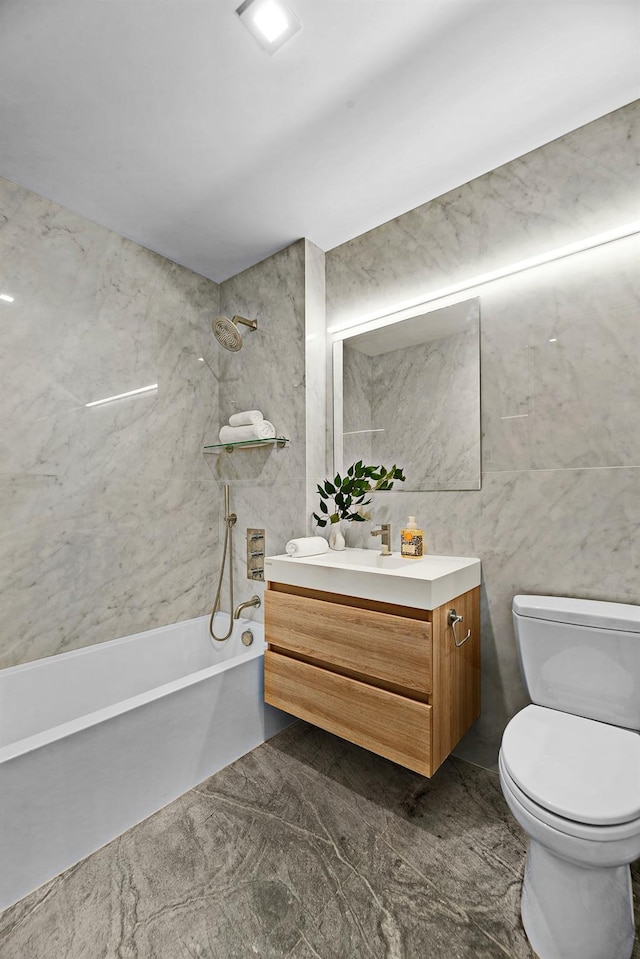 full bathroom featuring tiled shower / bath, vanity, tile walls, and toilet