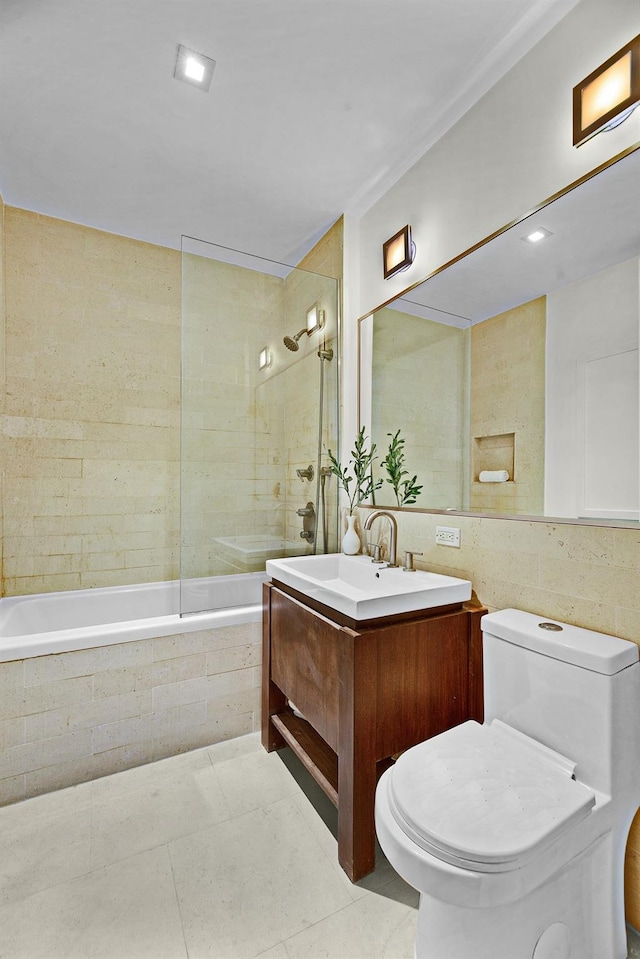 full bathroom featuring tile patterned floors, toilet, vanity, tile walls, and tiled shower / bath