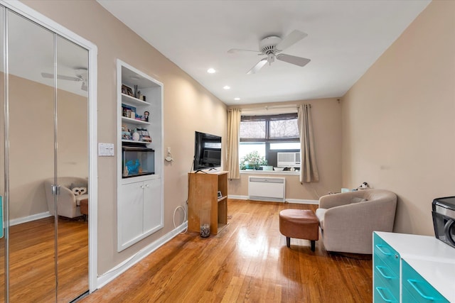 living area with hardwood / wood-style flooring, built in shelves, and ceiling fan