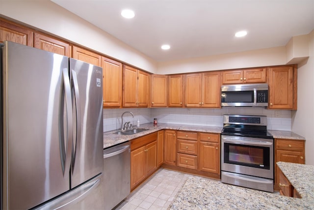 kitchen with light stone counters, sink, backsplash, and stainless steel appliances