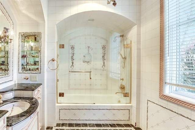 bathroom featuring vanity, shower / bath combination with glass door, and tile walls