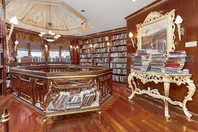 interior space featuring a chandelier, hardwood / wood-style floors, ornamental molding, and wood walls