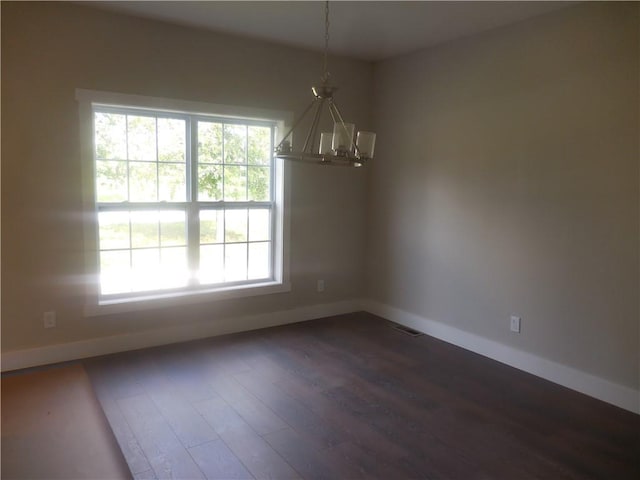 unfurnished dining area with a wealth of natural light, dark hardwood / wood-style flooring, and an inviting chandelier