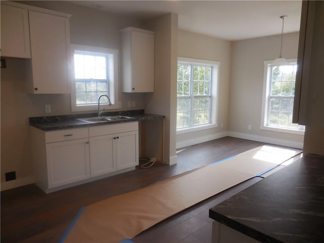 kitchen with hanging light fixtures, white cabinetry, sink, and a healthy amount of sunlight