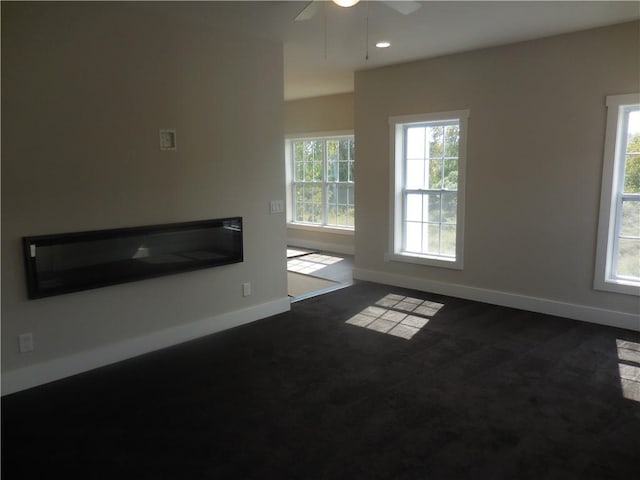 unfurnished living room featuring a wealth of natural light and ceiling fan