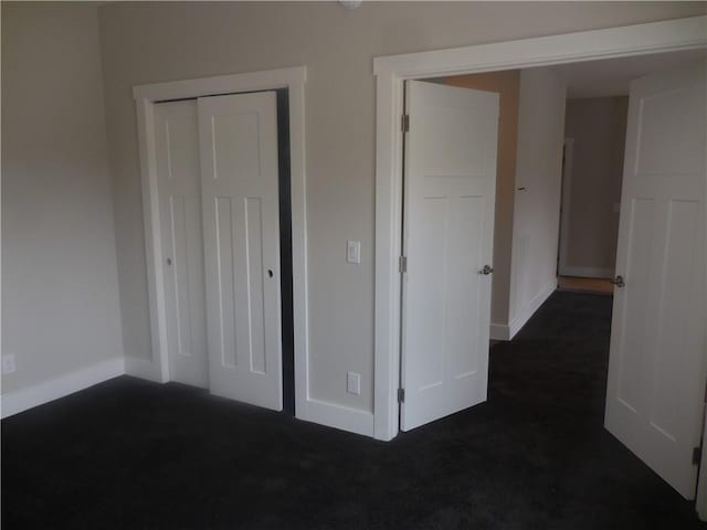 unfurnished bedroom featuring dark carpet and a closet