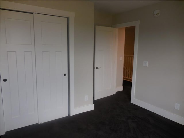 unfurnished bedroom featuring a closet and dark carpet