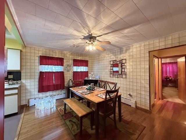 dining room featuring ceiling fan, wood-type flooring, and a baseboard heating unit