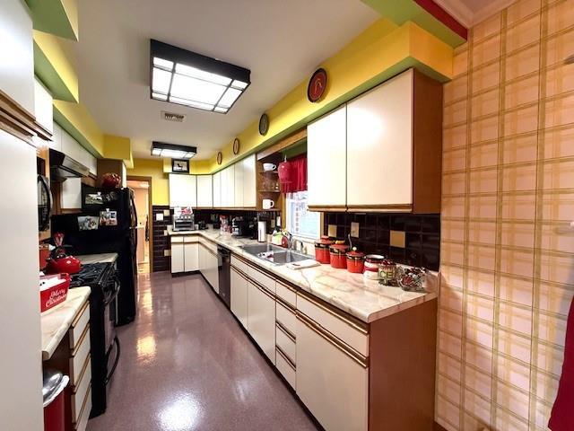 kitchen with white cabinets, black appliances, backsplash, and sink