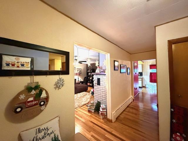 hallway with hardwood / wood-style floors, lofted ceiling, and a baseboard radiator