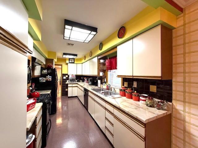 kitchen featuring white cabinets, black appliances, sink, and tasteful backsplash