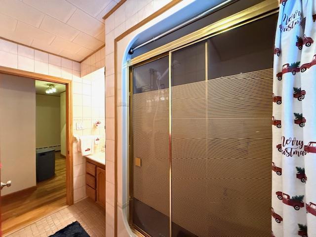 bathroom featuring walk in shower, hardwood / wood-style flooring, and tile walls