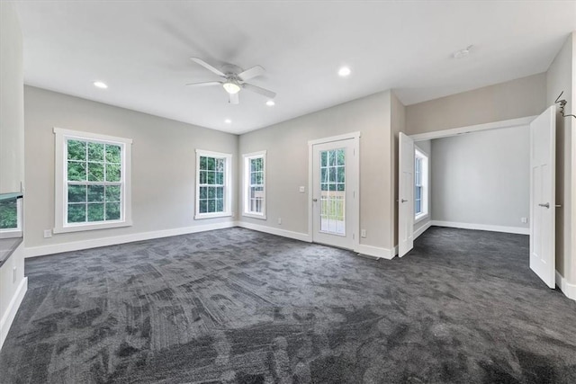 unfurnished living room featuring dark colored carpet and ceiling fan