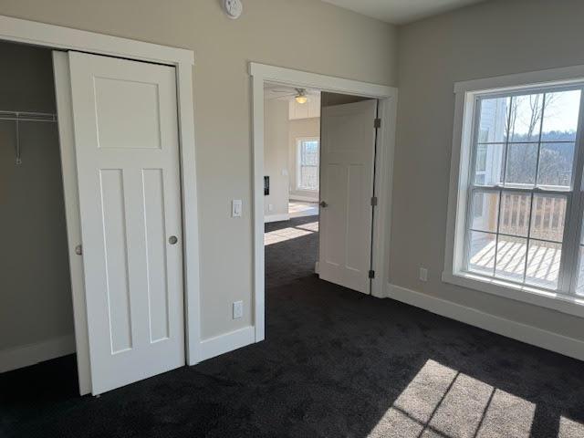 unfurnished bedroom with dark carpet and a closet