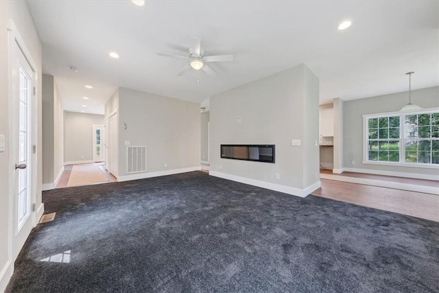 unfurnished living room featuring dark carpet and ceiling fan