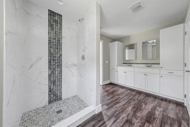 bathroom featuring a tile shower, vanity, and wood-type flooring