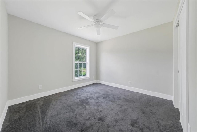 spare room featuring ceiling fan and dark colored carpet