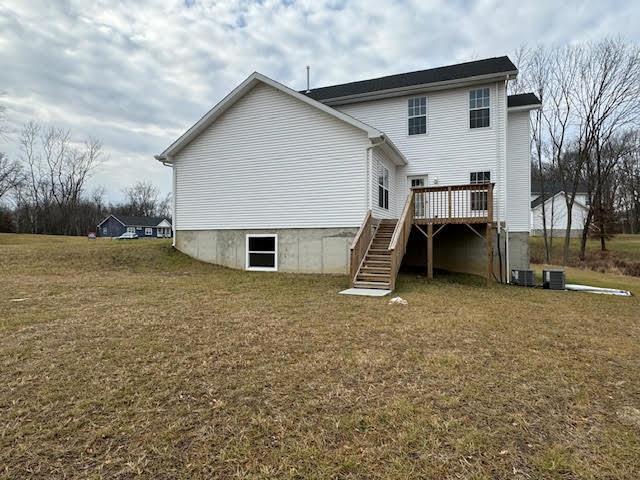 rear view of house featuring a lawn and a wooden deck