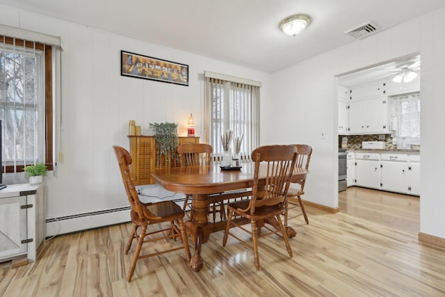 dining area featuring baseboard heating, ceiling fan, and light hardwood / wood-style flooring