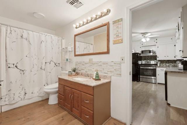 full bathroom featuring ceiling fan, tasteful backsplash, wood-type flooring, toilet, and vanity